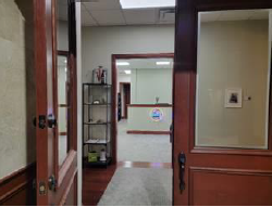 Office hallway with open door and shelves.