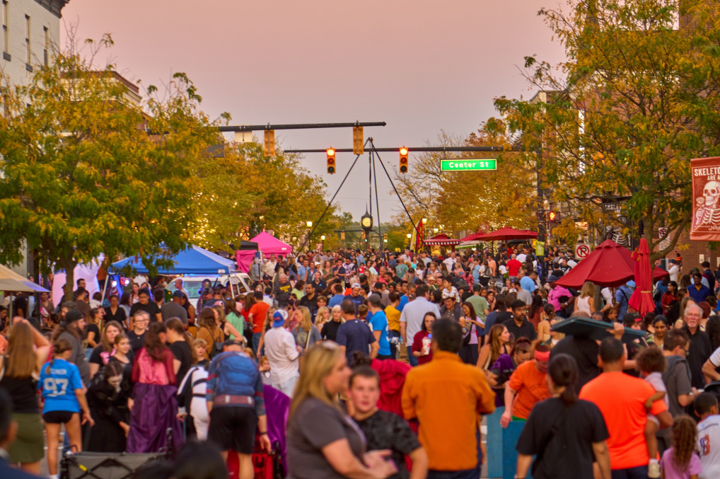 Crowded street festival at sunset with colorful tents.